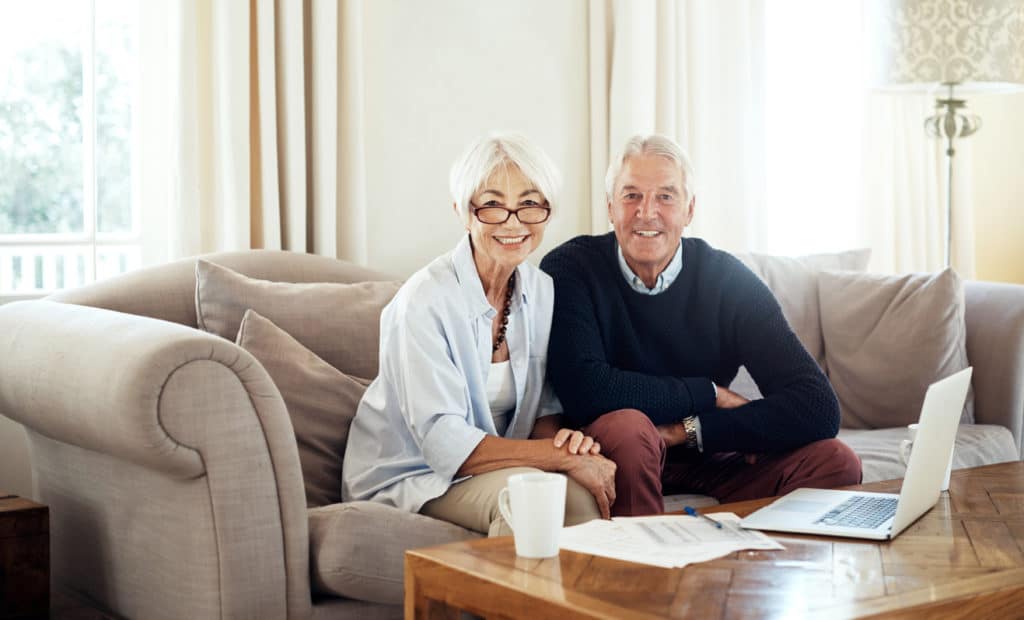 Old couple sitting on the couch smiling